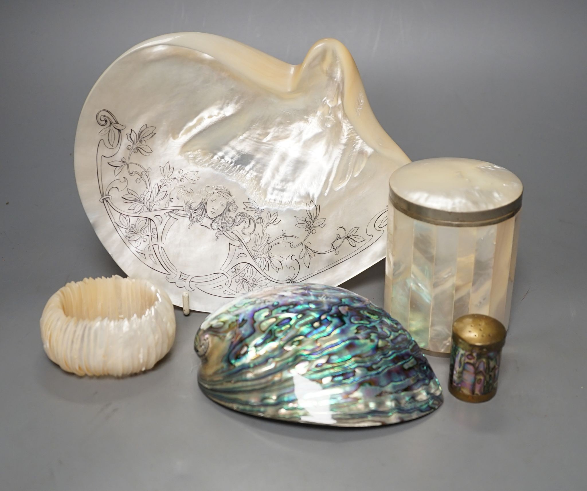 An engraved pearl shell, 22cm, a cylindrical box and bracelet, and two abalone shells